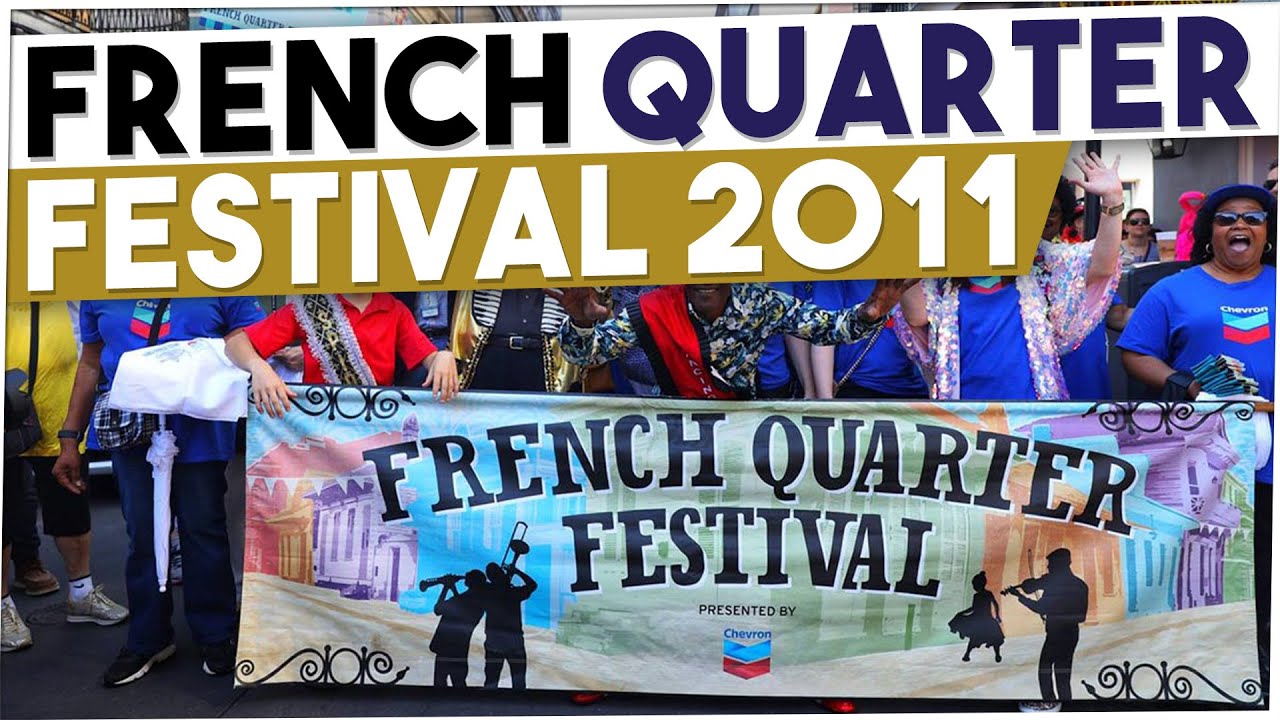 New Orleans French Quarter Fest 2011 video image. Image shows the FQF parade with the FQF sign and parade goers marching behind it on Bourbon Street in New Orleans.