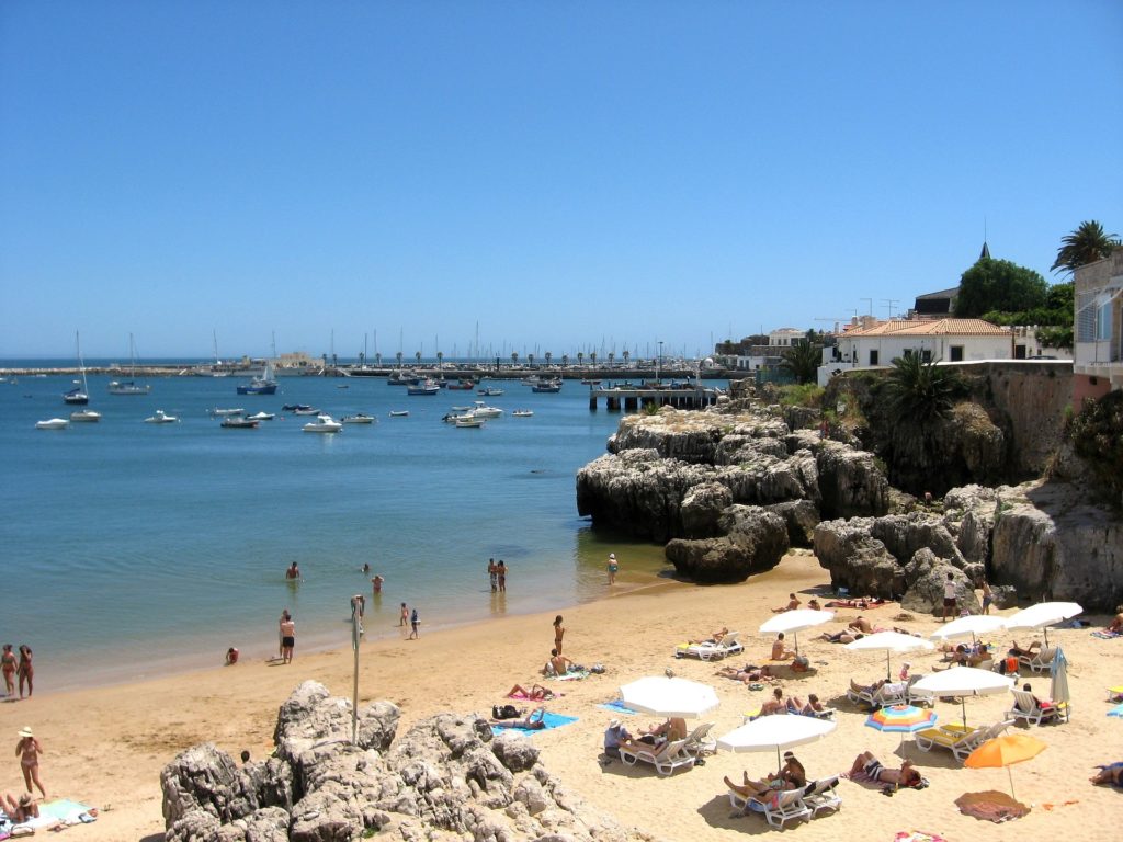 Sandy beach, rocky shoreline and boats along Portugal’s coast near Lisbon