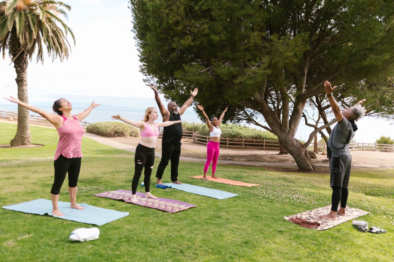 Diverse group of adults practicing yoga outdoors in a park