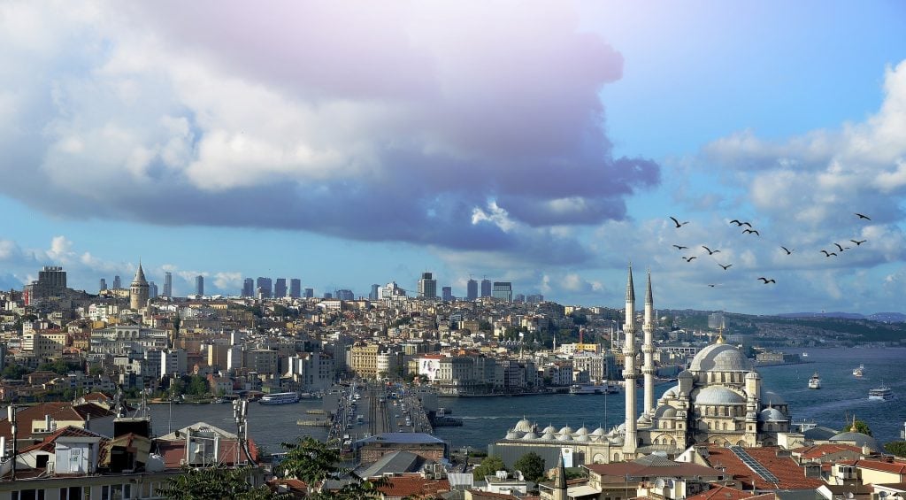 istanbul Panoramic view of Istanbul's waterfront skyline, Galata Bridge, Galata Tower and historic mosques beneath a cloudy sky.