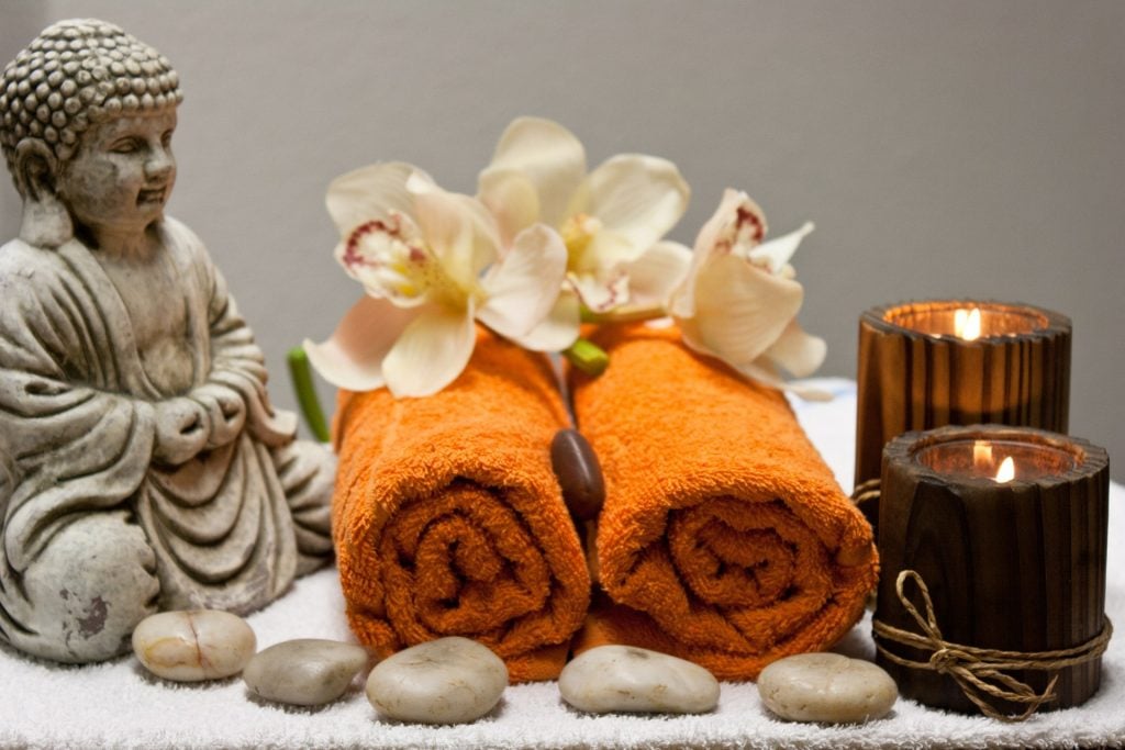 Spa setting with orange towels, orchids, candles and a small Buddha statue Spa setting with orange towels, orchids, candles and a small Buddha statue in Thailand