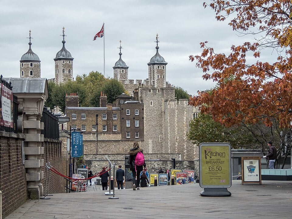 White Tower and surrounding buildings at the Tower of London framed by autumn foliage