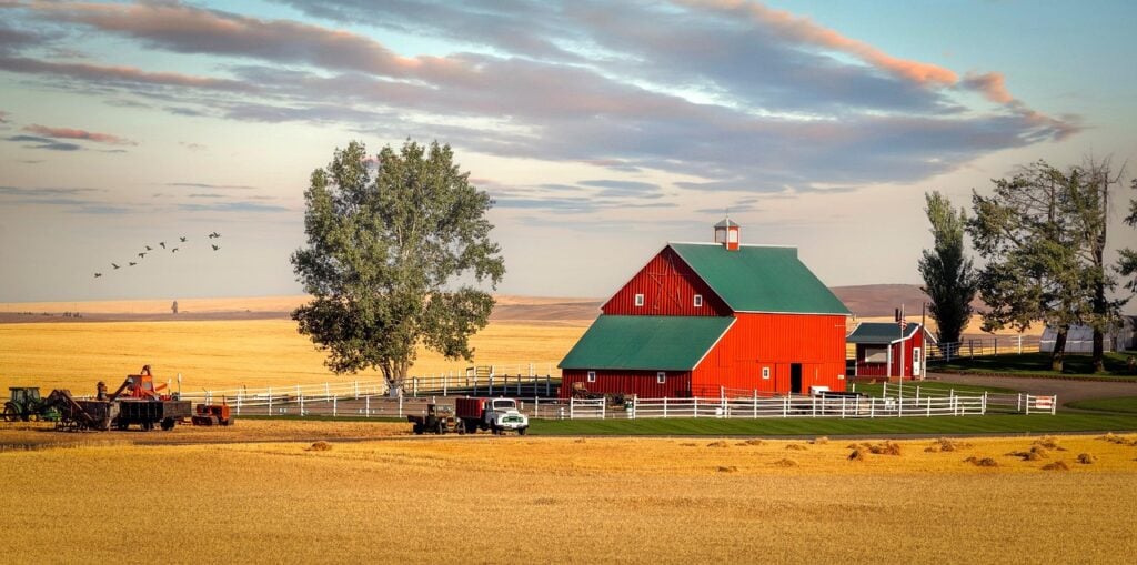 working farm barn agritourism Red barn surrounded by fields and farm equipment in the countryside