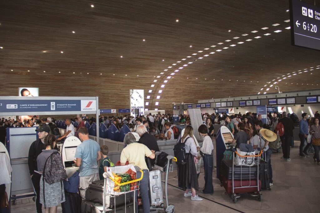 Crowded airport terminal Crowded airport terminal with passengers waiting in line with their luggage.