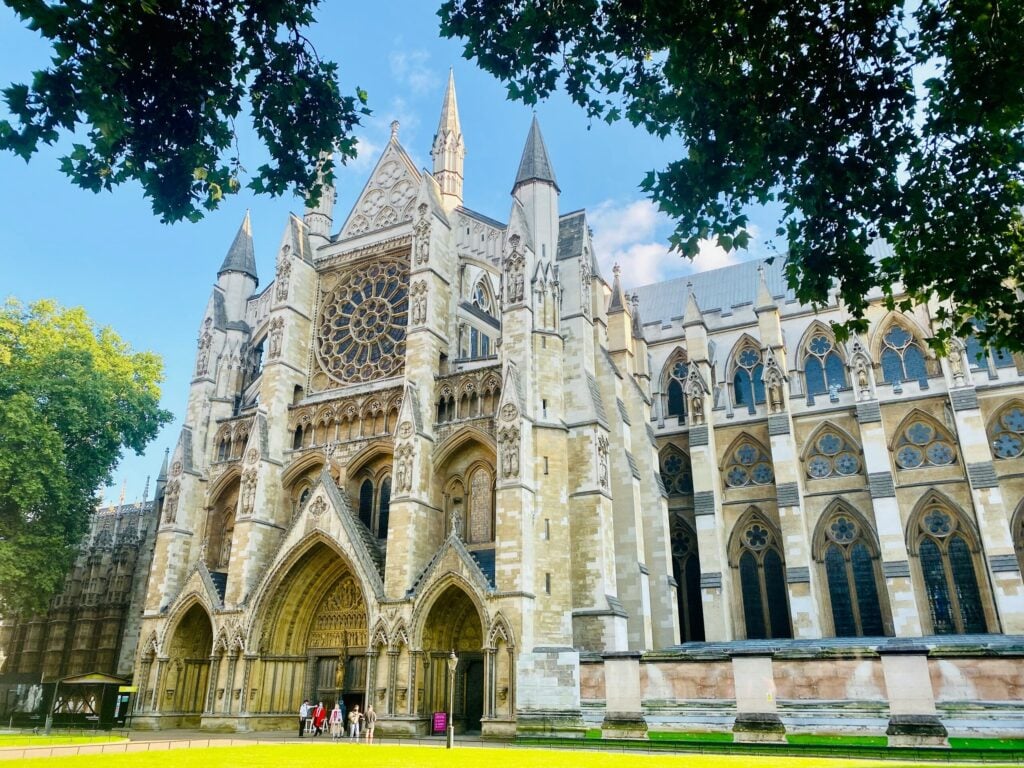 North entrance of Westminster Abbey in London beneath leafy treestowers