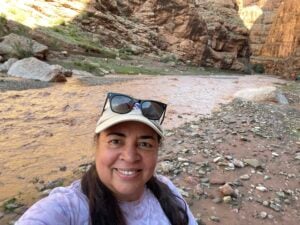 Tonya standing by a river in the High Atlas Mountains of Morocco as she takes a break from her trek.