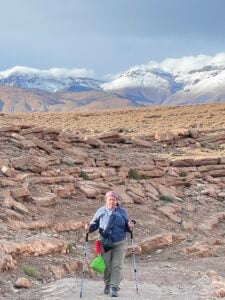 Tonya Fitzpatrck trekking in Morocco's High Atlas Mountains with beautiful snow-capped mountains in the background