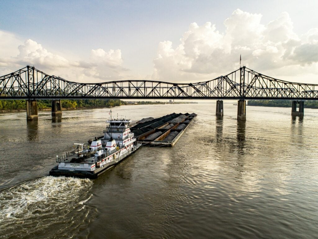 Photo by Justin Wilkens white and blue boat on Mississippi River under bridge during daytime