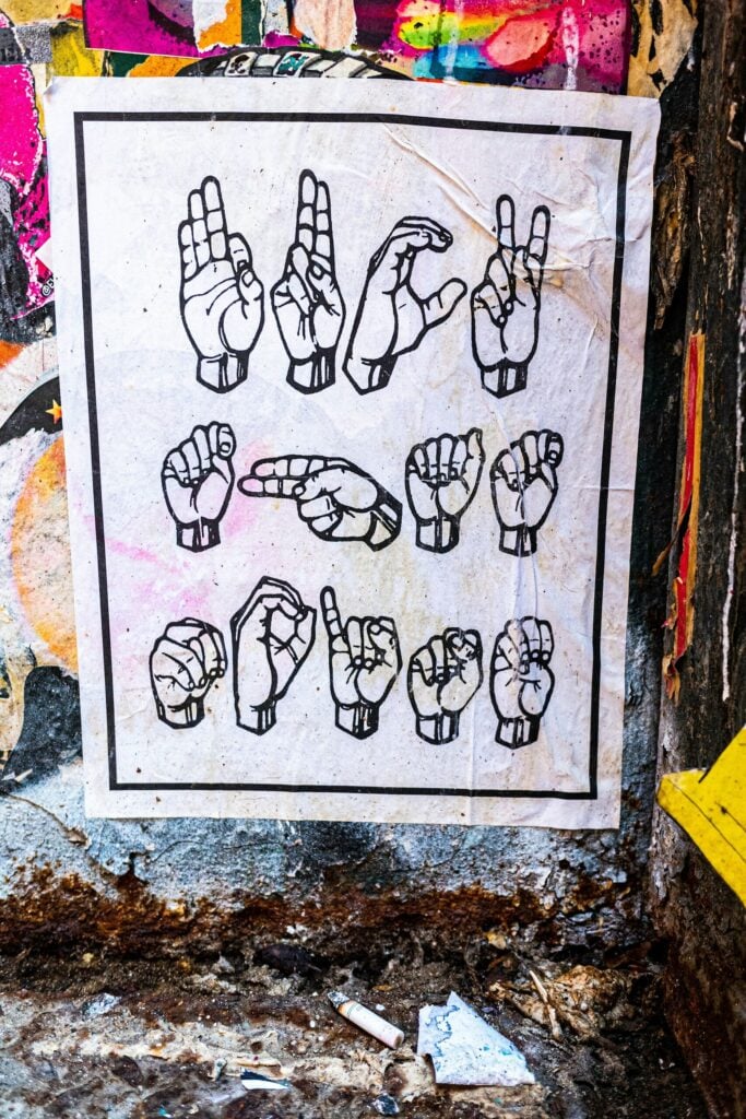 Photo by New York Said Hands forming american sign language alphabet on poster.
