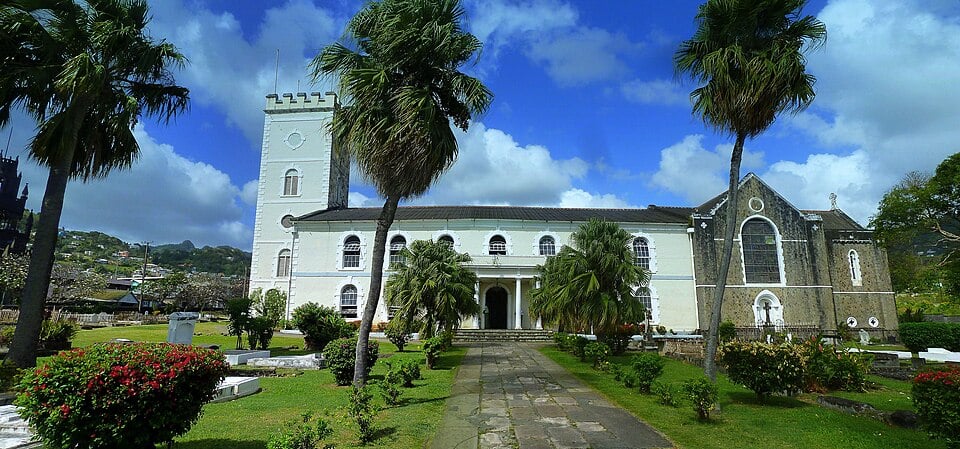 Kingstown St. George's Anglican Cathedra St. George’s Anglican Cathedral in Kingstown, St. Vincent, viewed across its palm-lined churchyard beneath a blue sky.