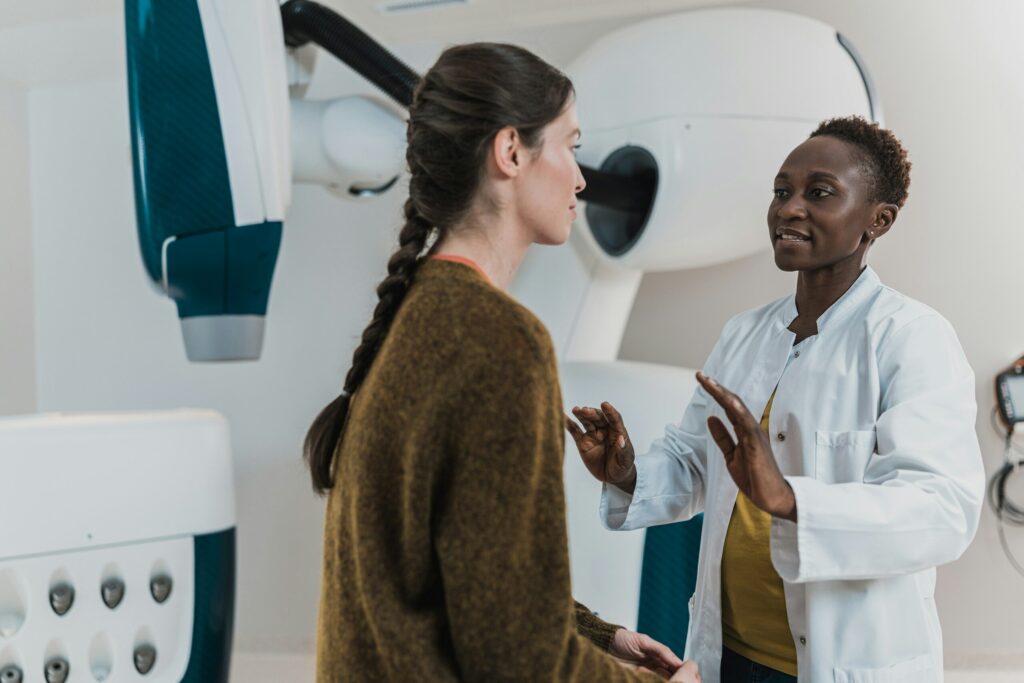 Doctor speaking with a patient beside medical imaging equipment
