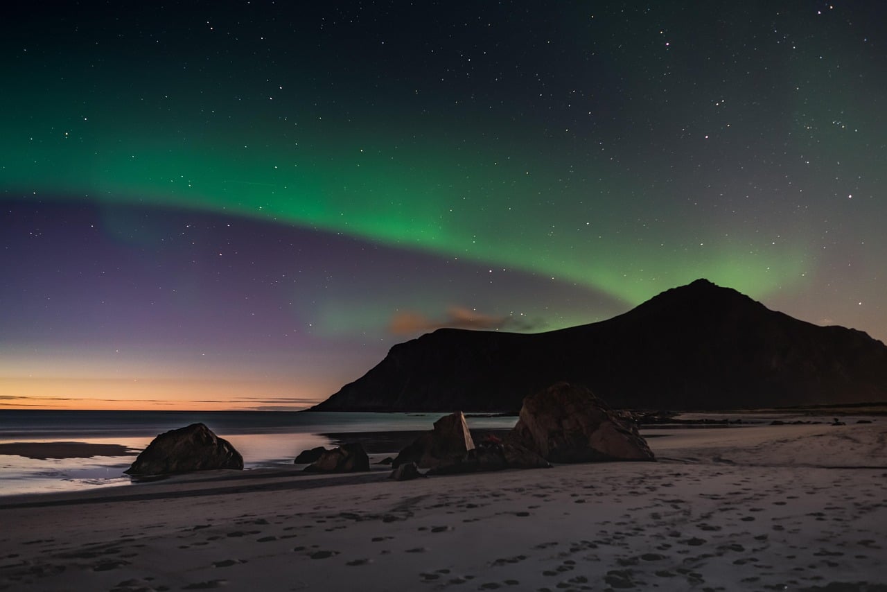 Travelers gather beneath the Northern Lights in Arctic Norway